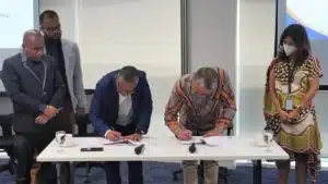 Individuals standing around a table signing documents